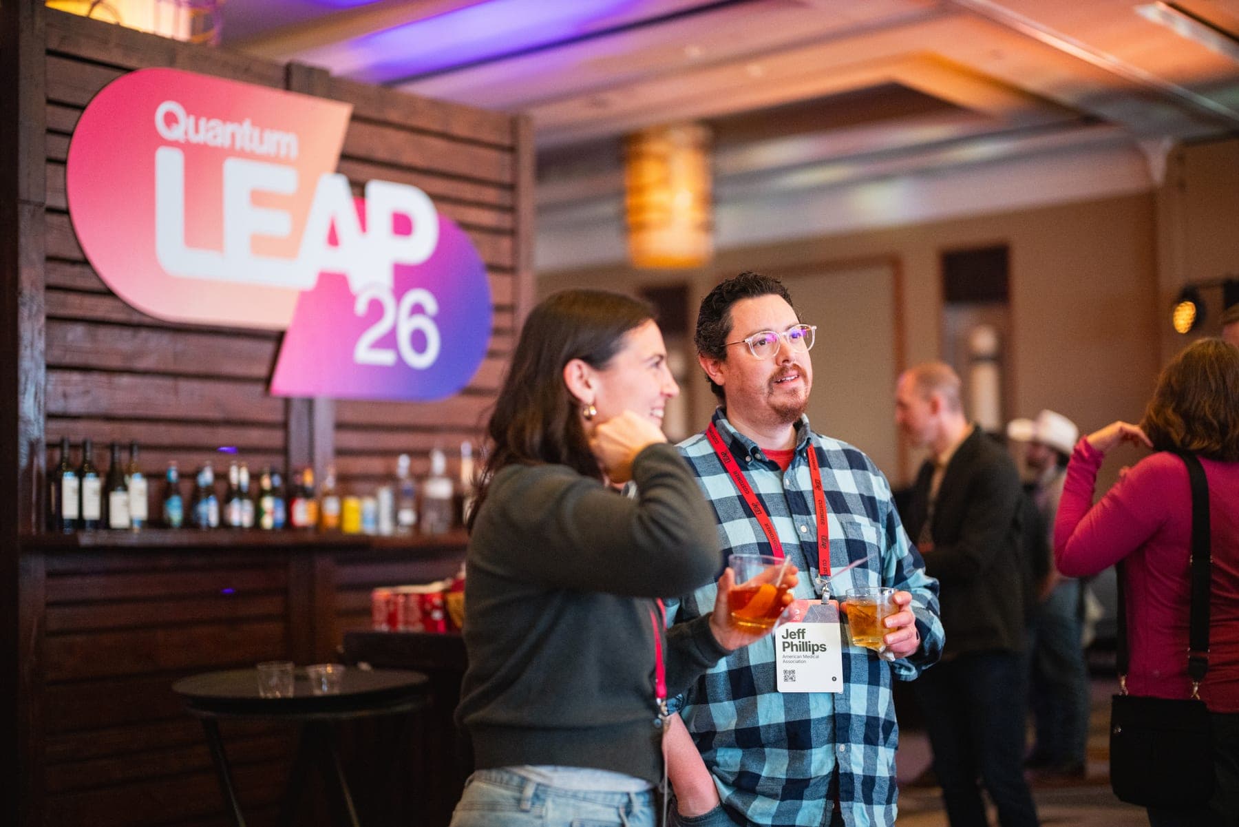 Two attendees chatting at a bar beneath a LEAP 26 sign